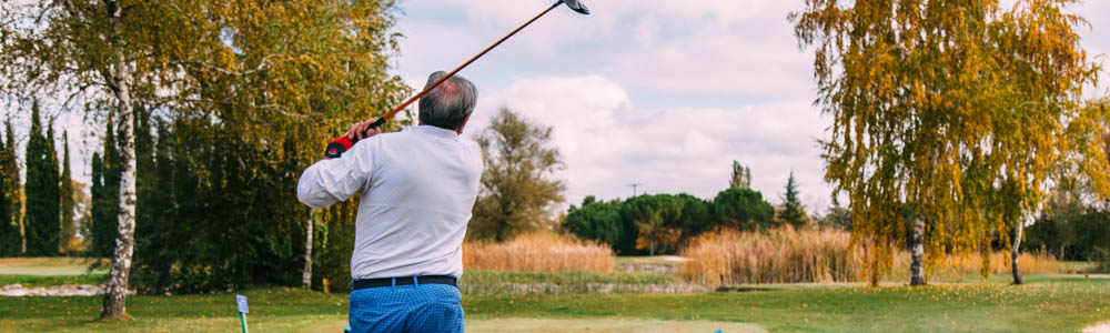 Older male golfer driving off on the golf course